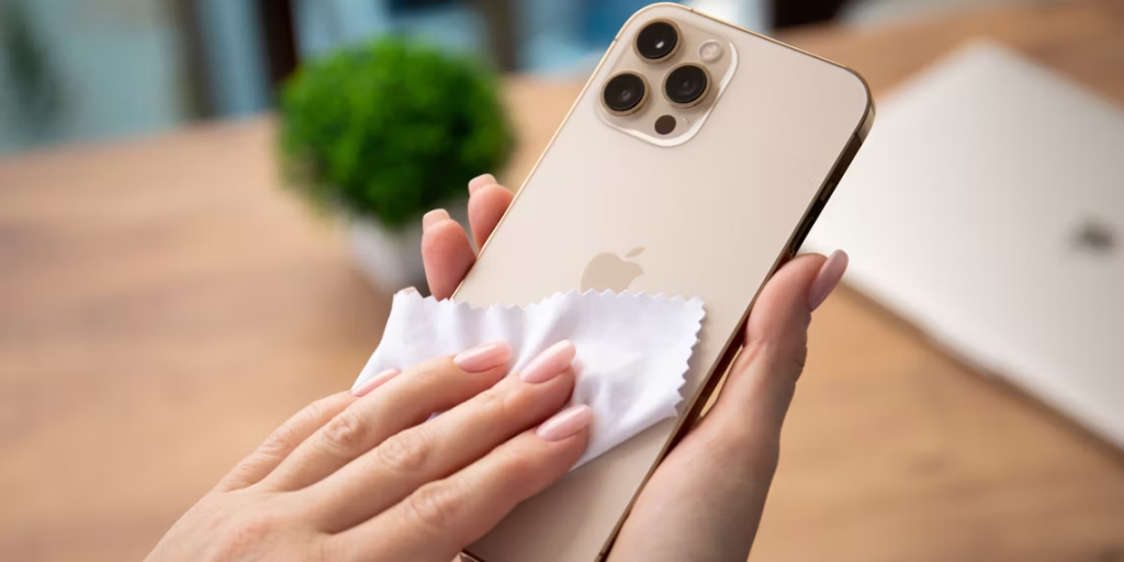 una mujer limpiando un iphone con un paño de microfibra